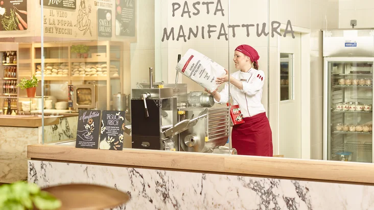 Eine Frau arbeitet in der Pasta Manifattura vom VAPIANO Berlin Alexanderplatz.