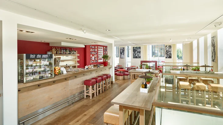 Innenaufnahme vom VAPIANO Leipzig mit Tischen und Stühlen und der Bar.