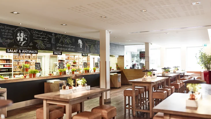 Innenaufnahme vom VAPIANO Göttingen mit Tischen, Stühlen und der Theke zum Bestellen im Hintergrund.