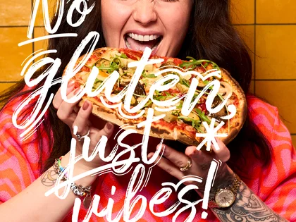 Eine Frau hält eine Pinsa und freut sich.