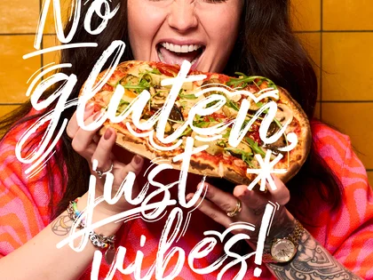 Eine Frau hält eine Pinsa und freut sich.