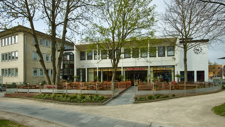 Außenansicht vom VAPIANO Göttingen mit einem großen Außenbereich mit Bänken und Pflanzen.