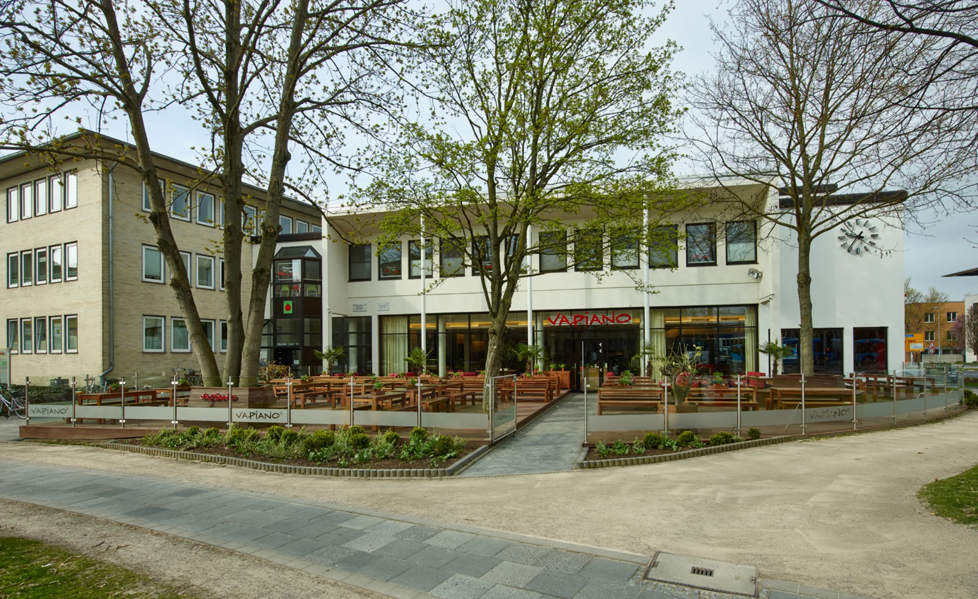 Außenansicht vom VAPIANO Göttingen mit einem großen Außenbereich mit Bänken und Pflanzen.