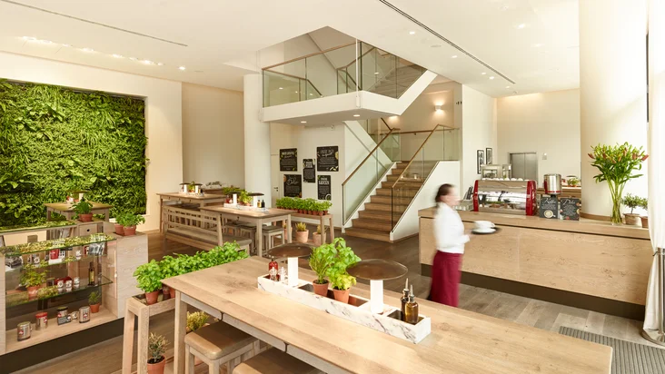 Innenaufnahme vom VAPIANO Berlin Alexanderplatz mit Tischen und einer Bar über zwei Etagen.