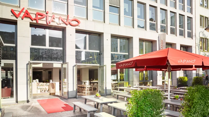 Außenansicht vom VAPIANO Bochum mit Bänken und Tischen im Außenbereich.