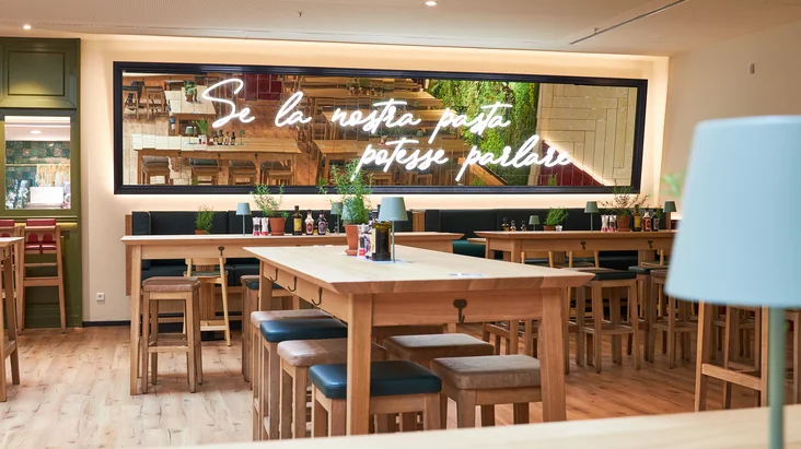 Innenaufnahme vom VAPIANO Hamburg Gänsemarkt mit einem Spiegel über den Sitzmöglichkeiten an der Wand.