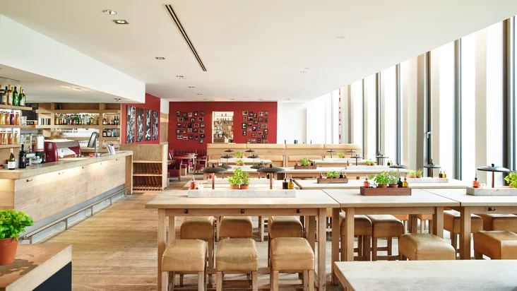 Innenaufnahme vom VAPIANO Köln mit Tischen und Stühlen und frischen Gewürzen.