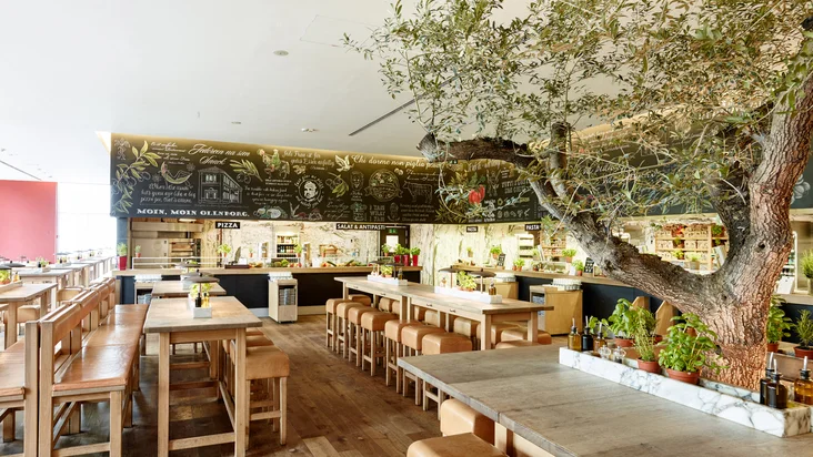 Innenaufnahme vom VAPIANO Oldenburg mit Sitzmöglichkeiten und der Theke im Hintergrund.