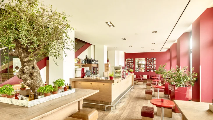 Innenaufnahme vom VAPIANO Mannheim mit Tischen, Hockern und einer Bar.