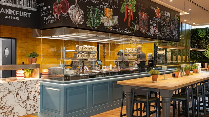 Innenaufnahme vom VAPIANO Frankfurt mit Tischen, Stühlen und der Theke zum Bestellen im Hintergrund.
