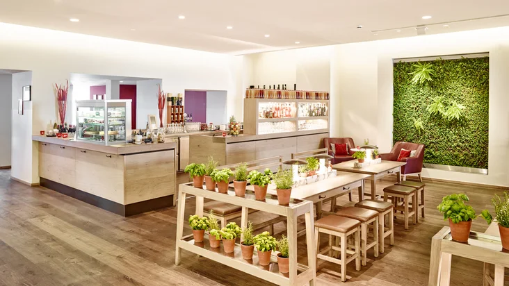 Innenaufnahme vom VAPIANO Bochum mit Tischen und frischen Kräutern und einer Bar im Hintergrund.