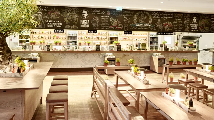 Innenaufnahme vom VAPIANO Bochum mit Tischen und einer Theke zum Bestellen im Hintergrund.