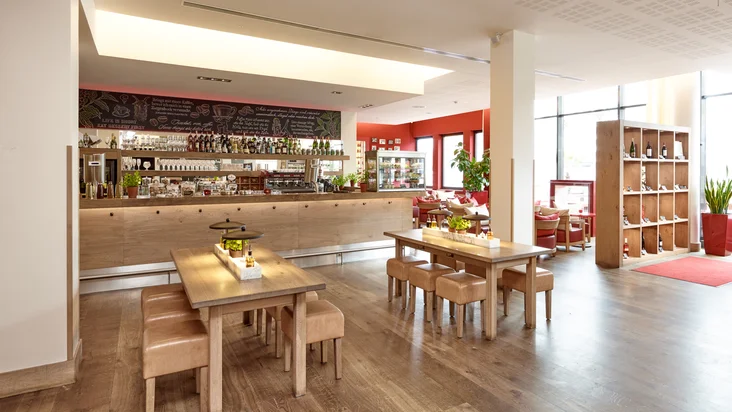 Innenaufnahme vom VAPIANO Göttingen mit Tischen, Stühlen und der Bar im Hintergrund.