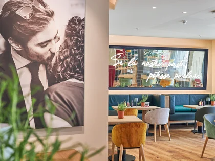 Innenaufnahme vom VAPIANO Hamburg Gänsemarkt mit einem dekorativen Foto an der Wand und einem Spiegel über den Sitzmöglichkeiten im Hintergrund.