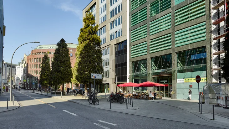 Außenansicht vom VAPIANO Hamburg Kurze Mühren mit Bänken und roten Sonnenschirmen.