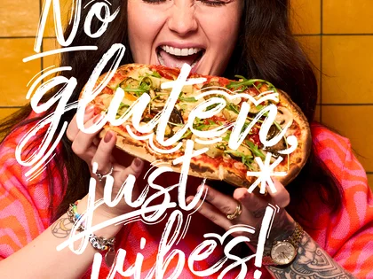 Eine Frau hält eine Pinsa und freut sich.