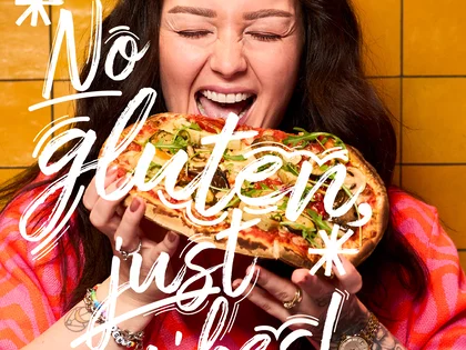 Eine Frau hält eine Pinsa und freut sich.