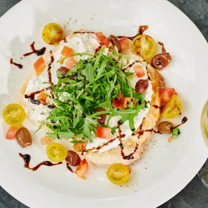 Links eine Bruschetta und rechts ein Insalata mit Feta und Melone. In der Mitte steht "More Drinks. More Fun! Summer Bundles"