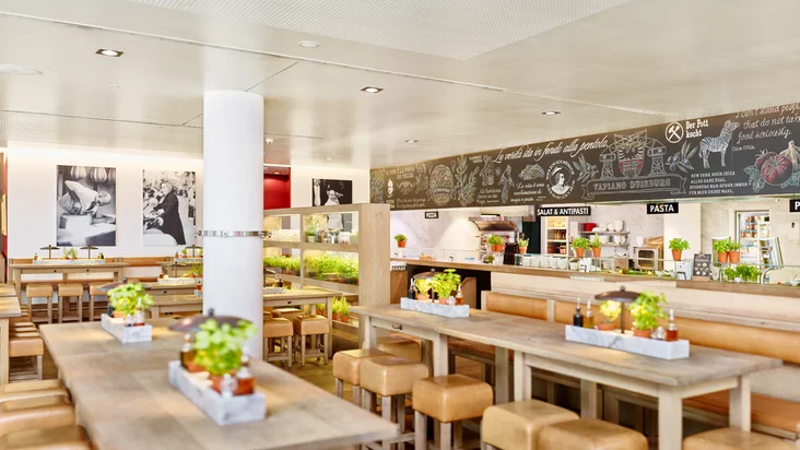 Innenaufnahme vom VAPIANO Duisburg mit Tischen, Stühlen und der Theke zum Bestellen im Hintergrund.